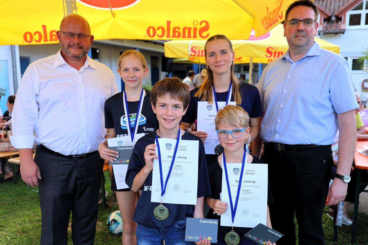 Bürgermeister Marcus Kretschmann (links) und Stadtverordnetenvorsteher Guido Funk mit den Riedstädter Sportler*innen der Inline Speedskating-Abteilung des Blau-Gelb Groß-Gerau bei der Sportlerehrung im letzten Jahr. Foto: Stadt Riedstadt