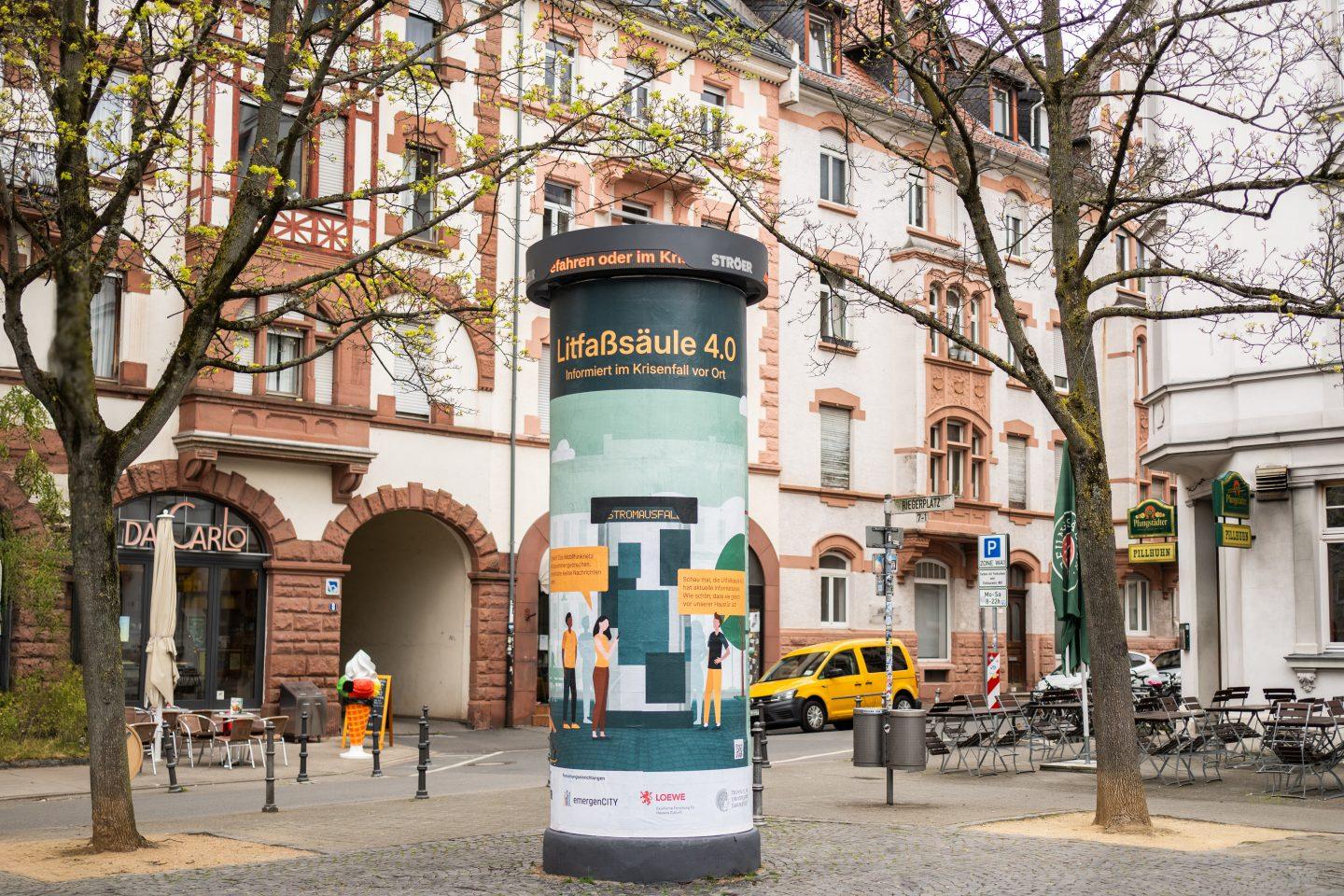 Die klassische, seit mehr als 170 Jahren bekannte Litfaßsäule erfährt eine Renaissance als Warnmultiplikator. Die Idee: Wenn bei einem langanhaltenden Stromausfall andere Kommunikationsmedien wie Mobilfunk, Internet oder Fernsehen ausfallen, kann die energieautarke Litfaßsäule 4.0 Menschen weiterhin informieren. Am Donnerstag (4.3.) nahmen das LOEWE-Zentrum emergenCITY, die Technische Universität Darmstadt und das Medienhaus Ströer den in einer gemeinsamen Forschungskooperation entstandenen Prototypen auf dem Riegerplatz in Darmstadt in Betrieb. Neben der technischen Erprobung sollen wissenschaftliche Untersuchungen im Anschluss zeigen, wie die Darmstädterinnen und Darmstädter die Warnsäule wahrnehmen. Im Bild: Installation der Säule auf dem Darmstädter Riegerplatz am 2. April 2024. Foto: Sascha Mannel