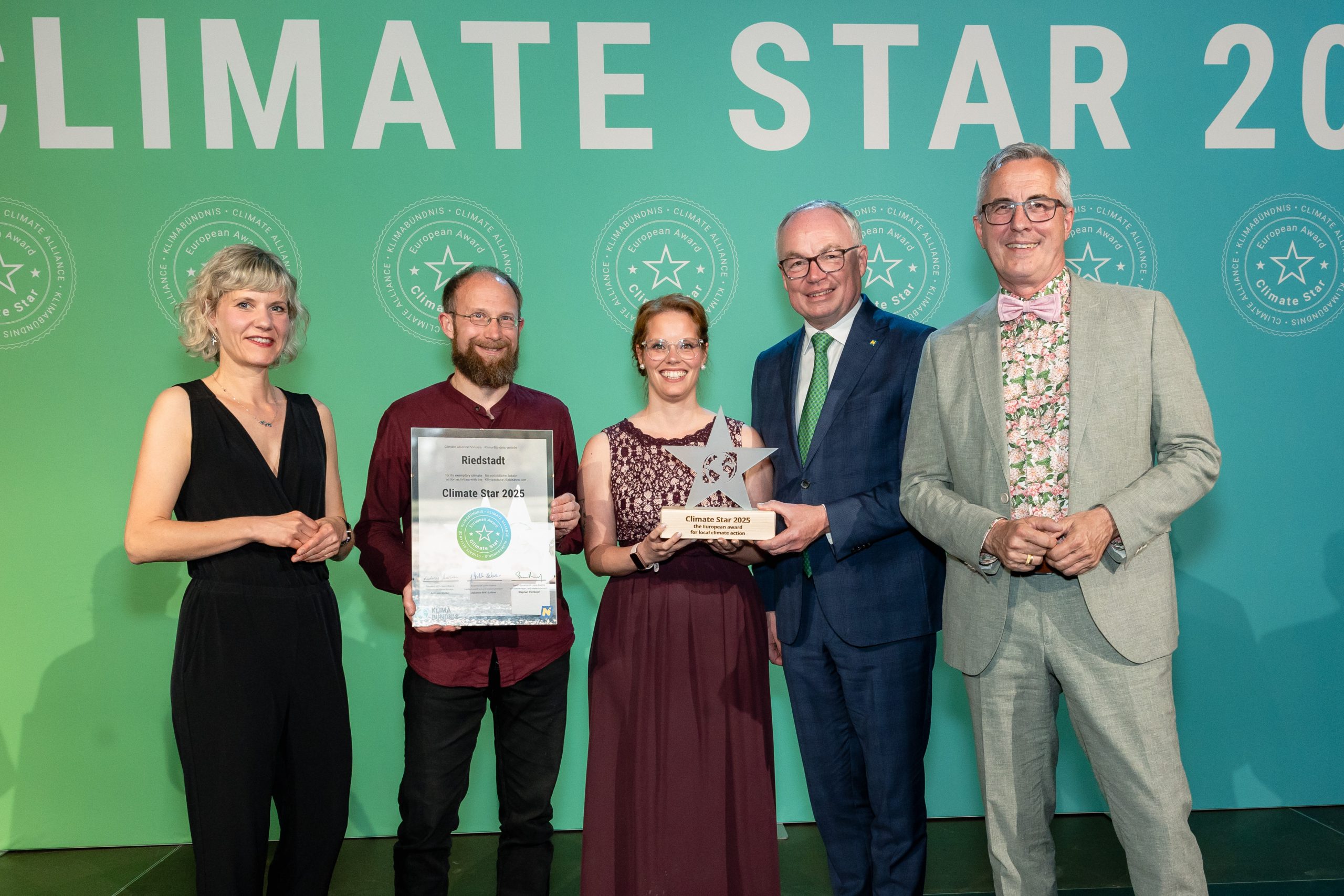 Bei der Preisverleihung umrahmen Elke Kastner, Geschäftsführerin des Klimabündnis Österreich und Dr. Stephan Pernkopf, Stellvertreter der Landeshauptfrau Niederösrerreichs sowie Andreas Wolter Bürgermeister von Köln und Vorstandsvorsitzender Klima-Bündnis Europa (rechts) Benjamin Krick und Sandra Seums von der Büchnerstadt Riedstadt. Foto: Braun & Nolz Media